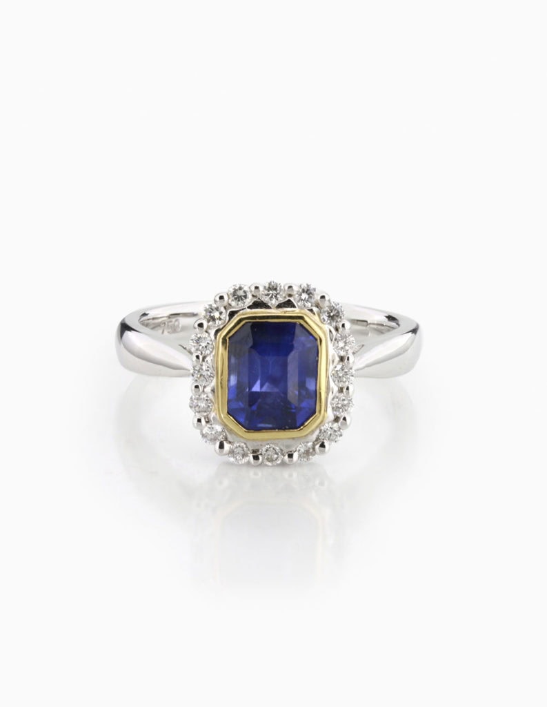 18ct white and yellow gold dress ring with a rectangular-cut sapphire in a yellow gold bezel and diamond halo