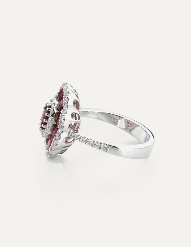 Side view of an 18ct white gold vintage-style cluster ring with rubies and a diamond halo, showing the pierced gallery