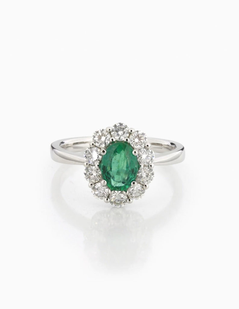 18ct white gold cluster ring with an oval emerald framed by a scalloped double diamond halo