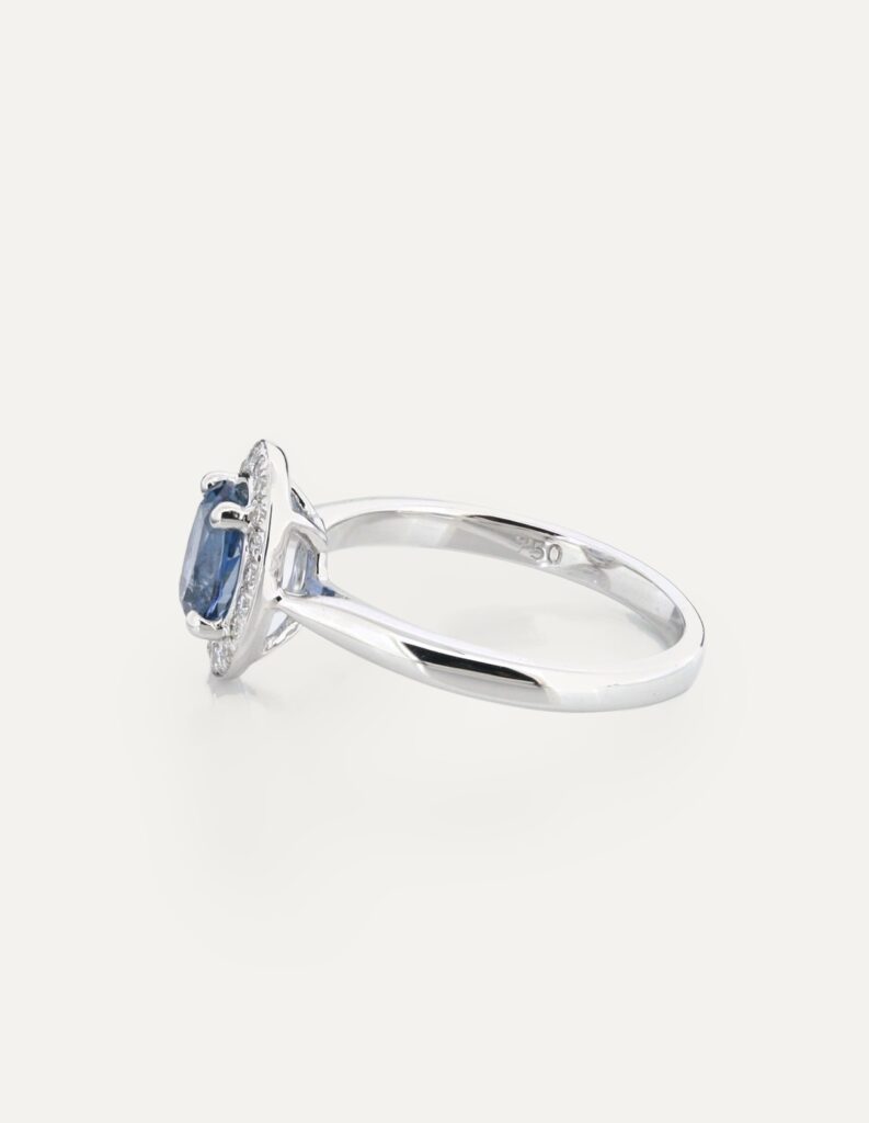 Side view of an 18ct white gold halo ring with an oval aquamarine and diamond halo