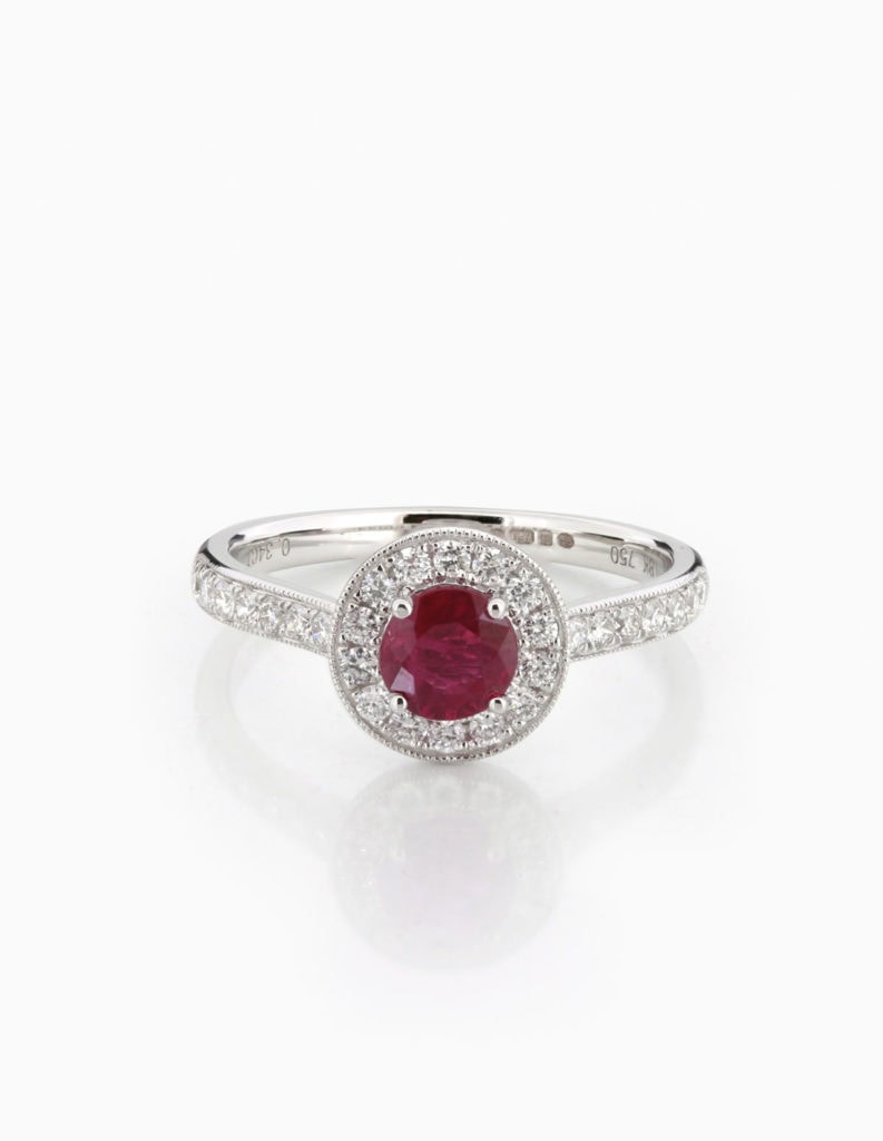 18ct white gold ruby and diamond halo ring with a round ruby framed by a diamond halo and pave shoulders