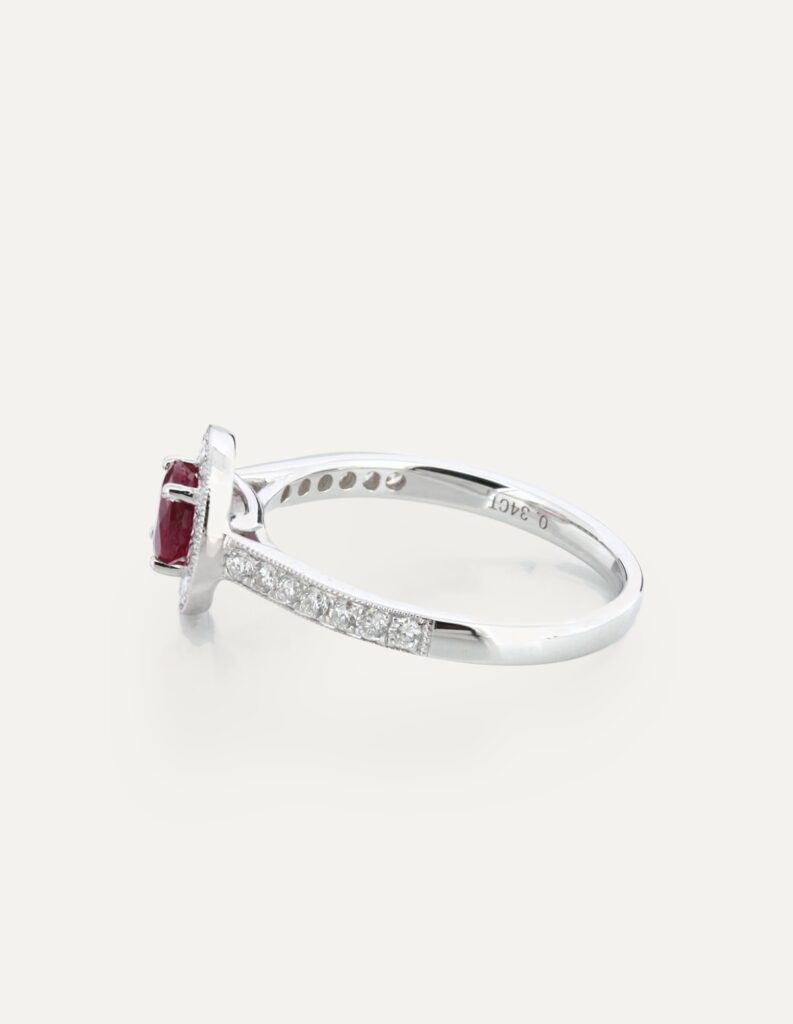 Side view of an 18ct white gold ruby and diamond halo ring showing the pave diamond shoulders