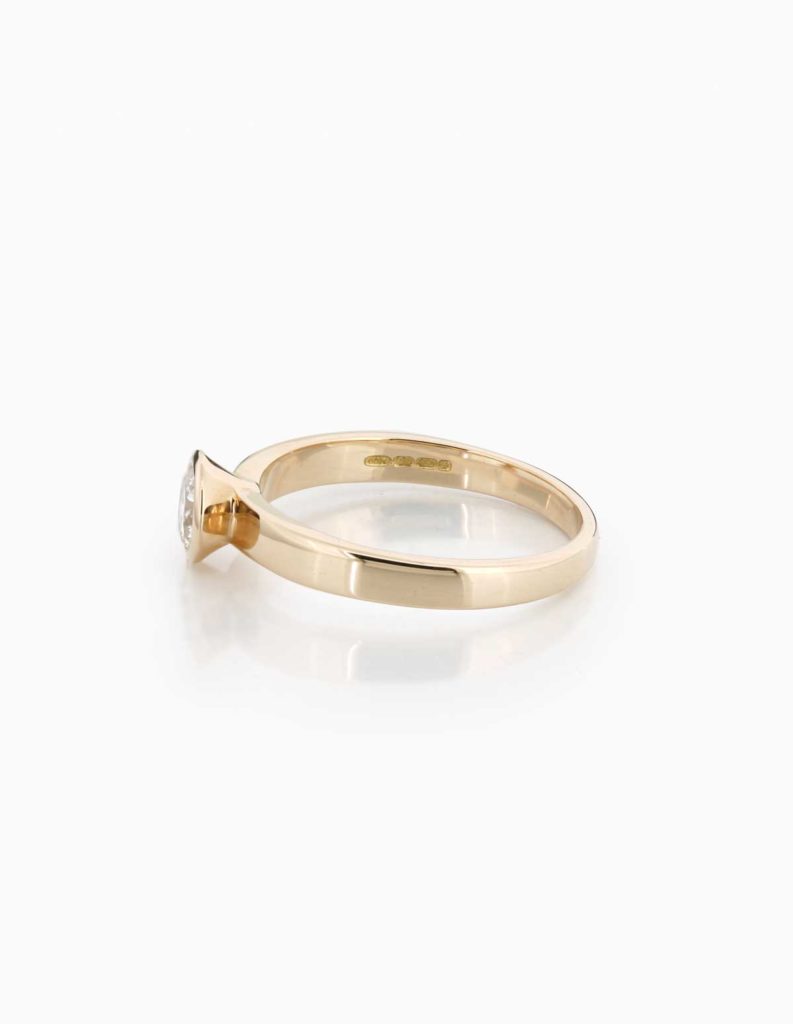 Side view of an 18ct rose gold solitaire ring with a bezel-set round diamond