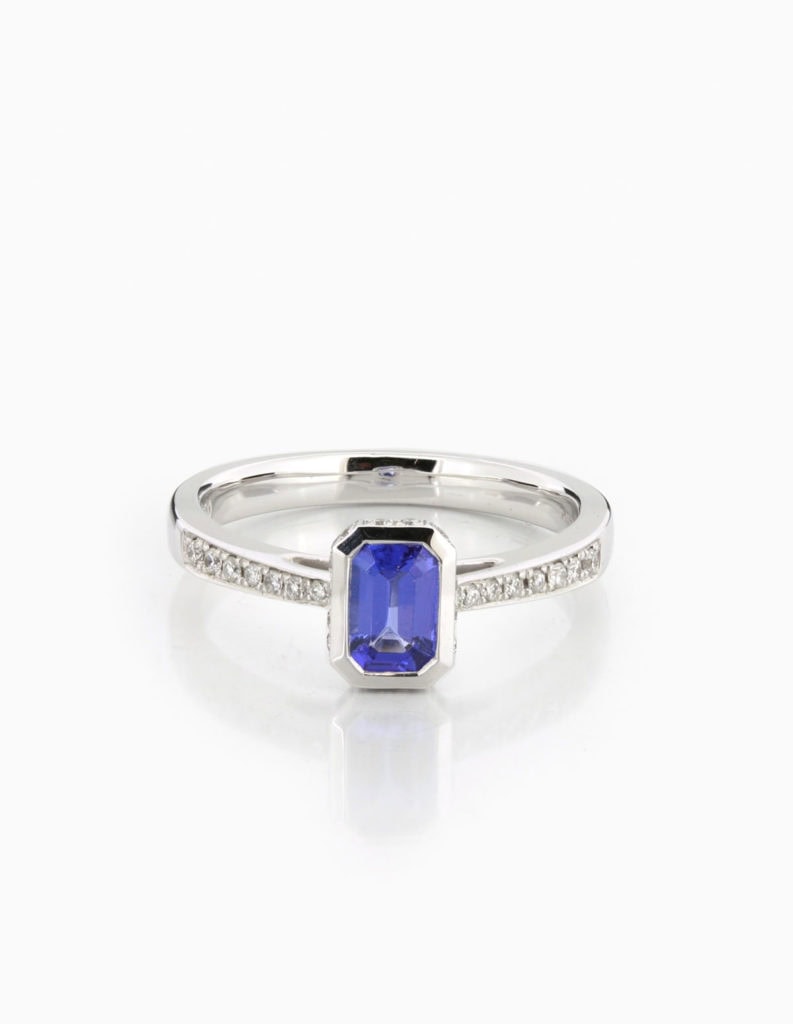 18ct white gold dress ring with a bezel-set emerald-cut tanzanite and pave diamond shoulders