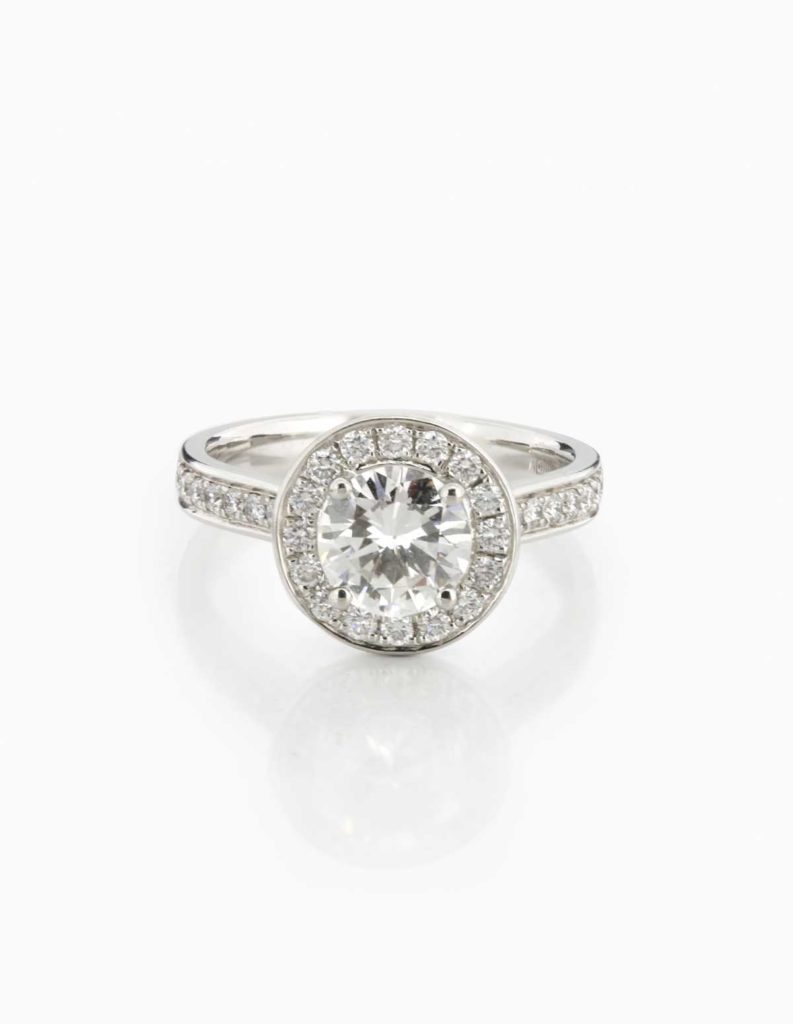 Platinum halo ring with a round brilliant diamond framed by a diamond halo and pave shoulders