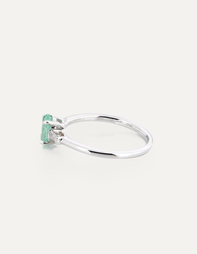 Side view of an 18ct white gold three-stone ring with an emerald-cut Paraiba tourmaline and tapered baguette diamonds