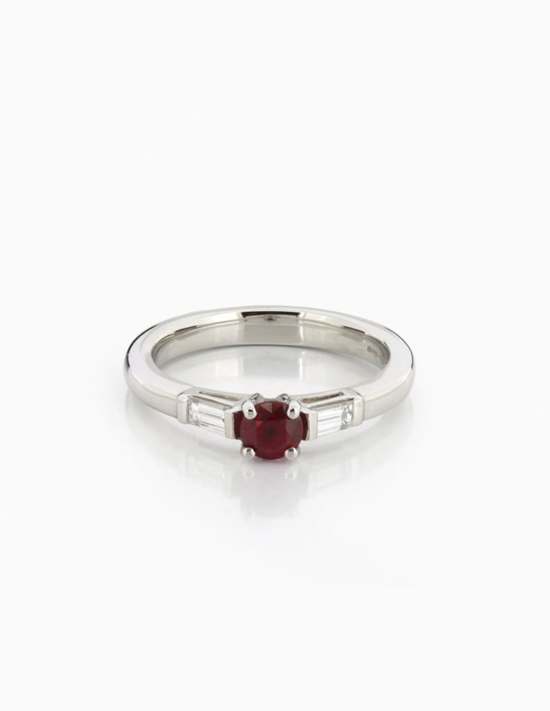 Platinum three-stone ring with a central round ruby flanked by two baguette-cut diamonds