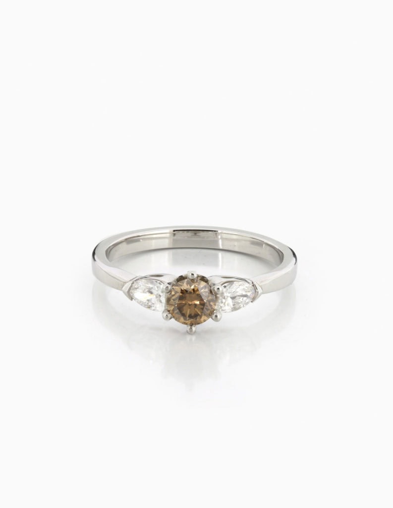 Platinum three-stone ring with a central round brilliant diamond flanked by two pear-shaped diamond shoulders