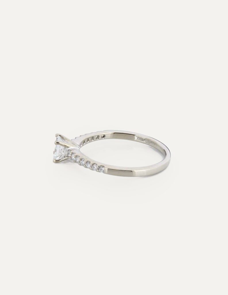 Side view of an 18ct white gold solitaire ring with a princess-cut diamond and pave diamond shoulders