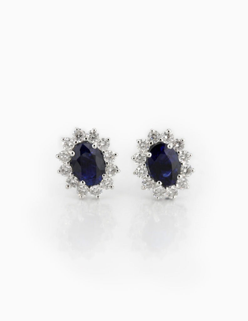 18ct white gold cluster earrings with an oval sapphire framed by a round diamond halo