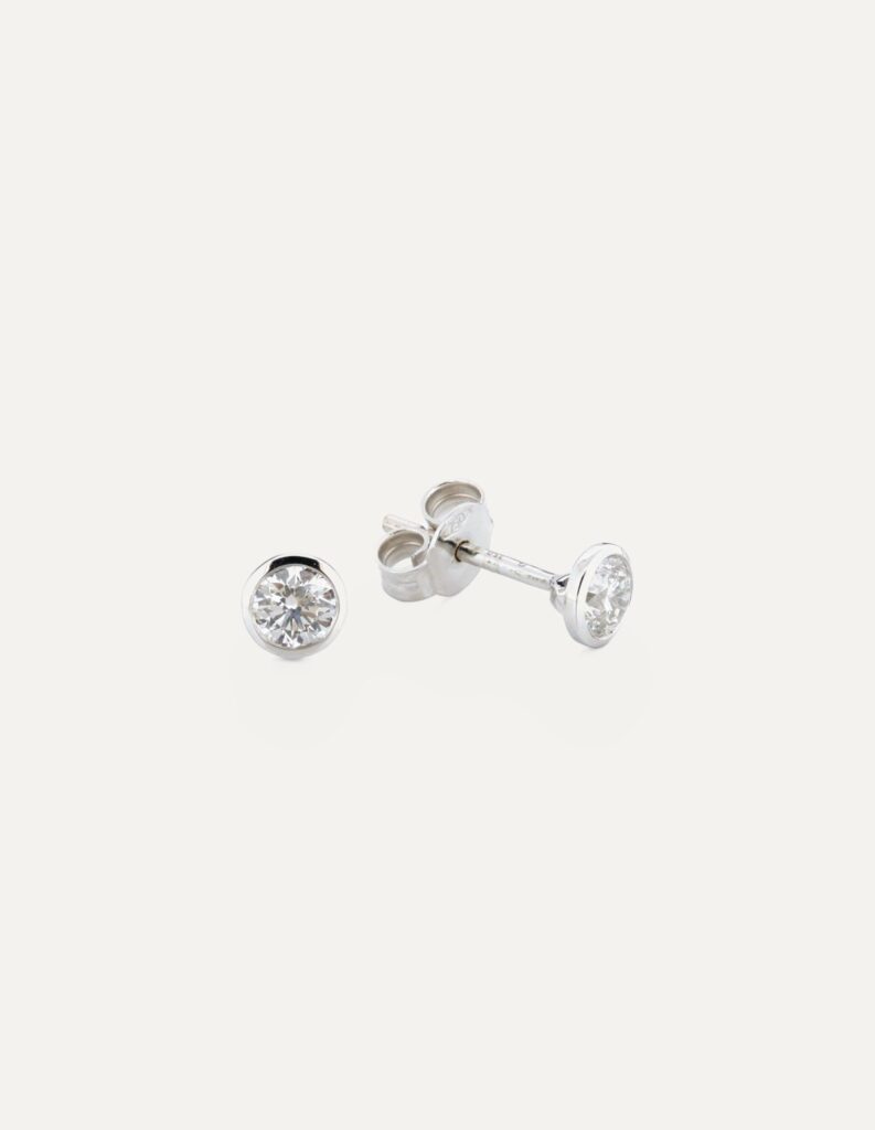 Pair of 18ct white gold rub-over set round diamond stud earrings, shown with the post and butterfly back