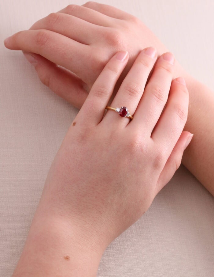 A red ruby and diamond 3 stone ring on hands