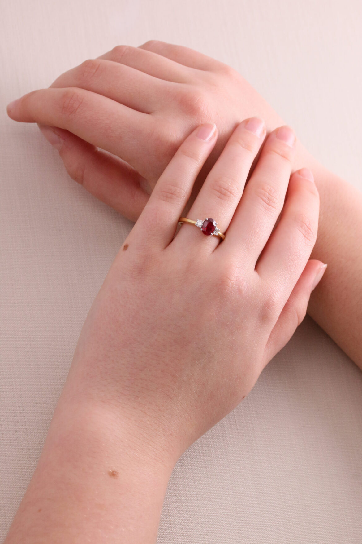 A red ruby and diamond 3 stone ring on hands