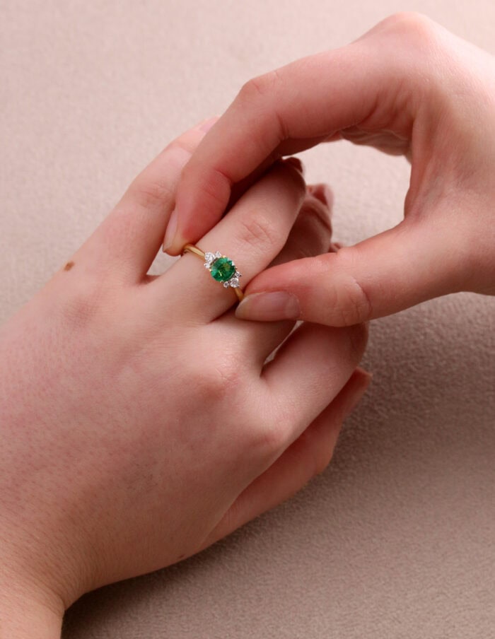Dress ring oval centre emerald 0.70ct with diamond side stones 0.17ct GSI 18ct yellow gold ring size M