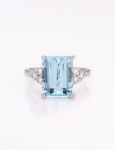 Large emerald cut Aquamarine blue stone Ring WIth three diamonds eother side of the cnetral stone on a white metal band