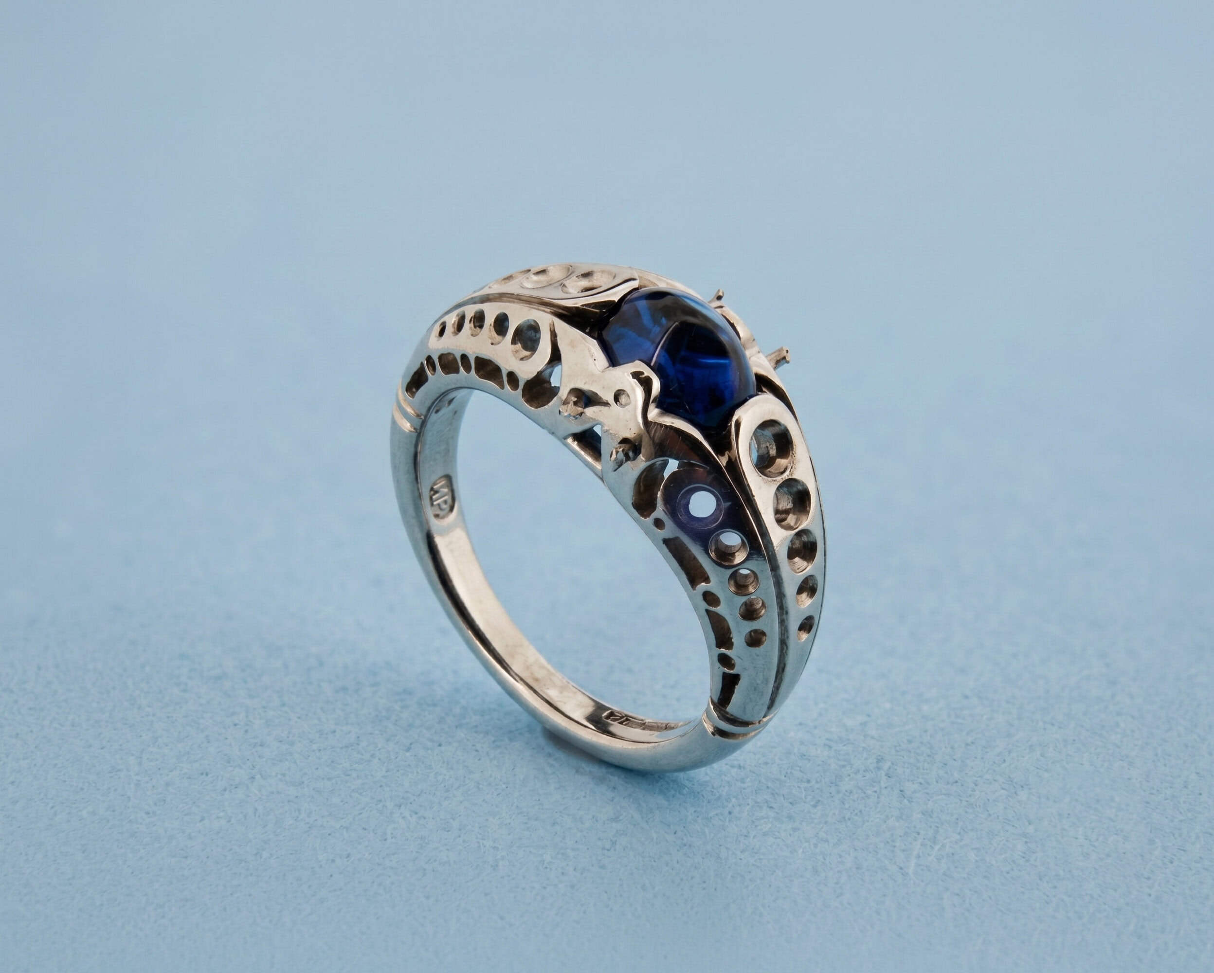 The white gold ring part-made — drilled settings and cut-out gallery visible before the side diamonds are set