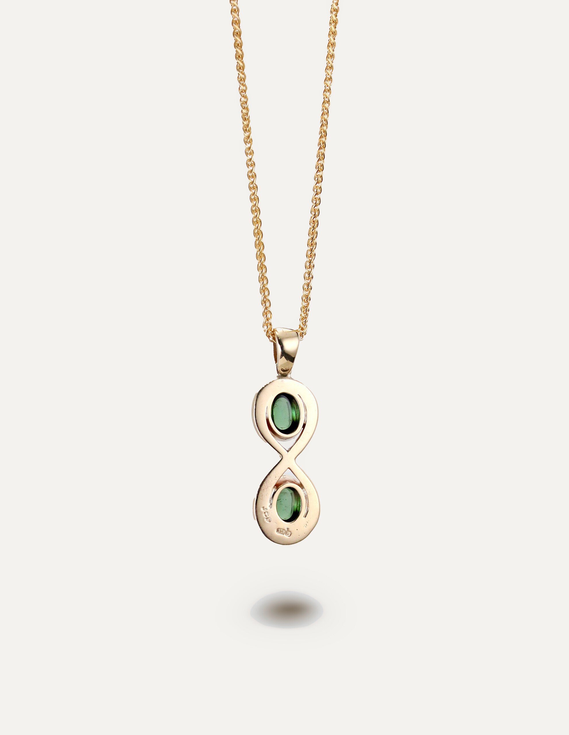 One-off 9ct gold infinity pendant set with two green tourmaline cabochons on a spiga chain