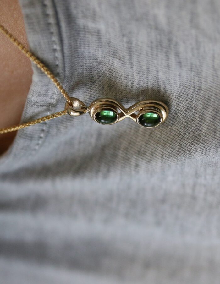 One-off 9ct gold infinity pendant set with two green tourmaline cabochons on a spiga chain